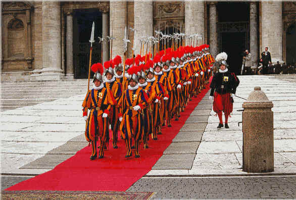 Um destacamento de guardas su��os desce os degraus da imponente Scalla Regia no Vaticano. O ambiente se conserva precisamente como na Renascen�a. Nada indica, nos trajes, nas armas, no pr�dio, que estamos em 1956. � que o Vaticano nos oferece um exemplo magn�fico de fidelidade ao passado. Mas ao mesmo tempo, os Papas, e Pio XII de modo todo particular, t�m introduzido no Pal�cio Apost�lico todos os melhoramentos capazes de servir ao bom andamento dos assuntos eclesi�sticos. Os escrit�rios, o Banco, o Correio, o Governatorado do Vaticano t�m sido equipados com o que h� de melhor. Harmoniosa fus�o entre os valores oferecidos por todos os s�culos, inclu�do o nosso, para a boa ordena��o do trabalho e da vida. Luminosa express�o de que tradi��o e progresso podem e devem coexistir e completar-se, segundo planos da Provid�ncia.